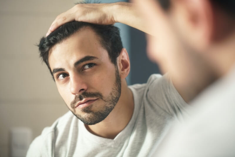 man looking at hair in mirror