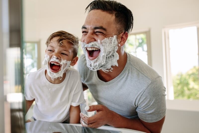 man with young son shaving and smiling in mirror