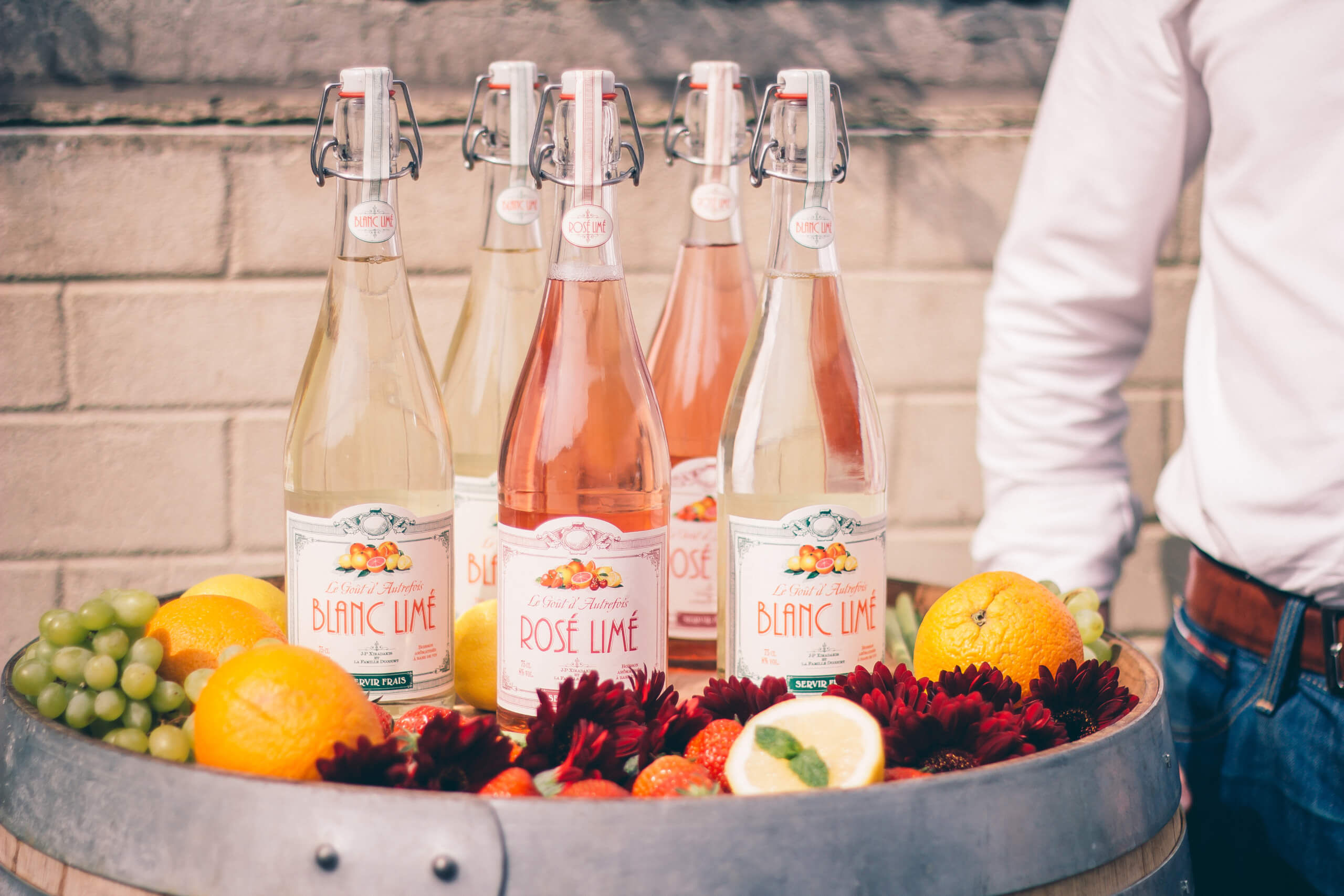 Bouteille de Blanc et de rosé Limé, posées sur une barrique de vin.