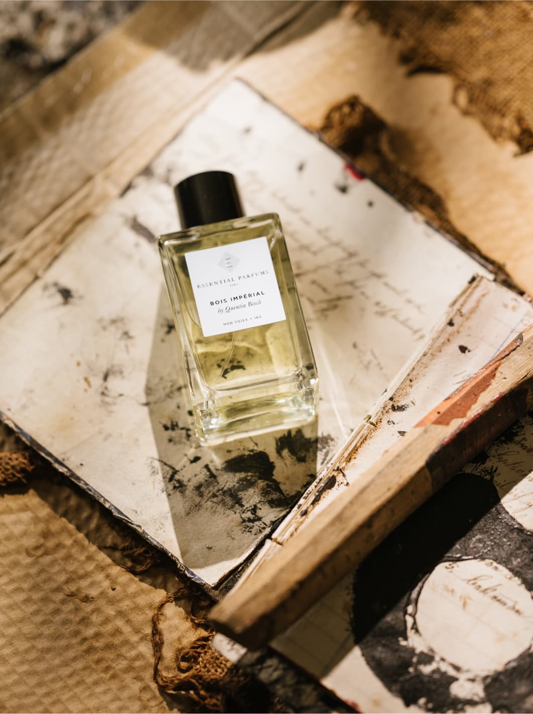 Flacon des Unisex Nischenduftes Bois Imperial von Essential Parfums auf einem antiken Buch mit Handschrift