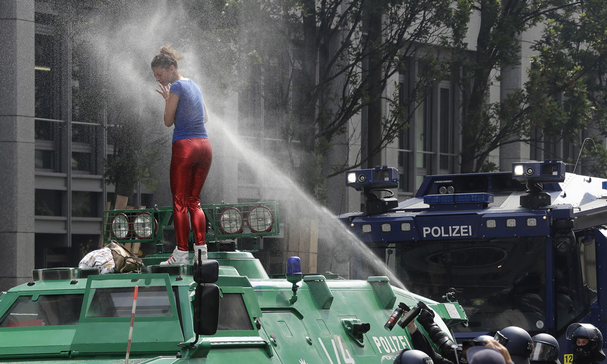 Woman in a blue and red outfit getting pepper-sprayed