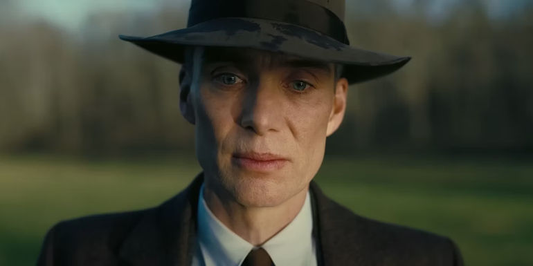 Oppenheimer looks down with a solemn look on his face in Oppenheimer.