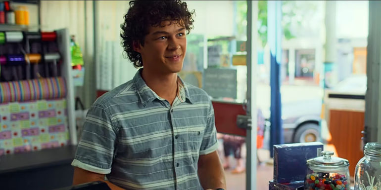 Older Eli Bell smiles while at the pharmacy in Boy Swallows Universe.