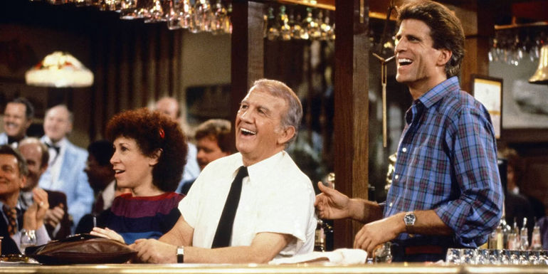 Sam, Coach, Carla, and others smiling at a bar in Cheers season 1