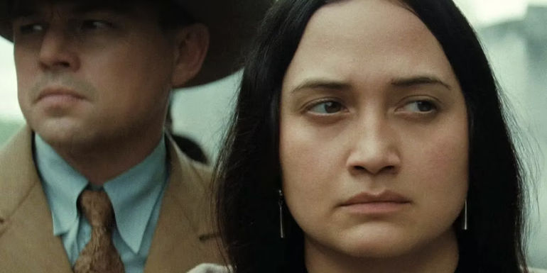 Mollie looks angry and Ernest stands behind her in The Killers of the Flower Moon.