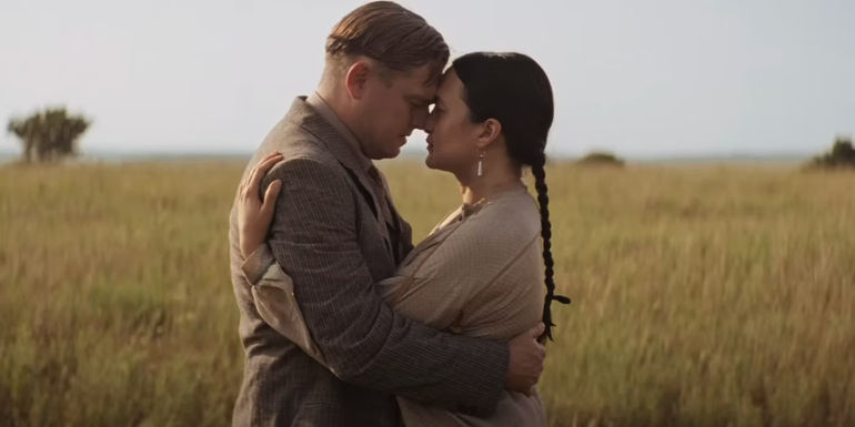 Leonardo DiCaprio as Ernest Burkhart and Lily Gladstone as Mollie Burkhart in a field in Killers of the Flower Moon