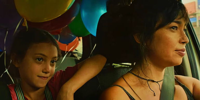 Sol and her mother in the car with balloons behind them in Tótem