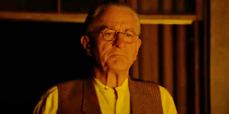 Robert De Niro as William Hale illuminated by firelight in Killers of the Flower Moon