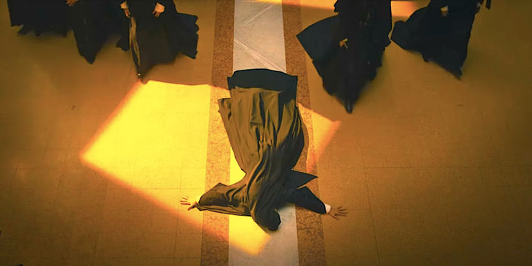 A nun lies on the ground in the shape of a cross as others walk past her in The First Omen trailer