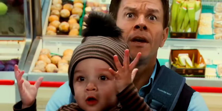 Mark Wahlberg as Dan Morgan Looking Shocked While Holding a Baby in a Grocery Store in The Family Plan