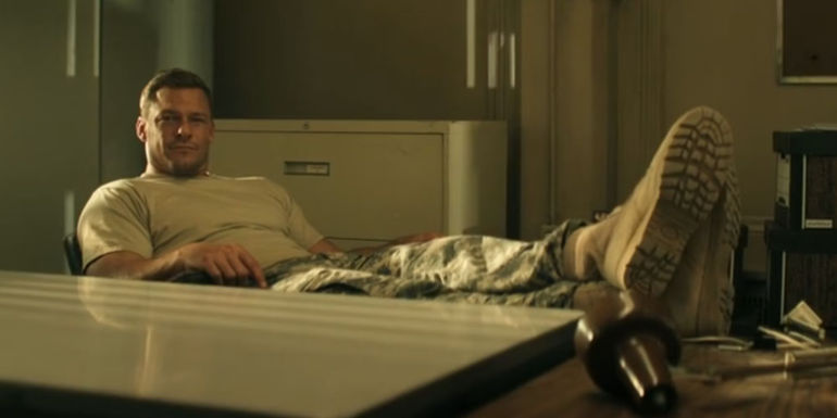 Alan Ritchson with his feet up on his desk as Reacher