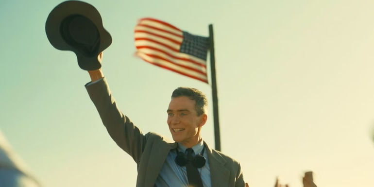 Cillian Murphy as J. Robert Oppenheimer celebrates in front of an American flag in Oppenheimer.