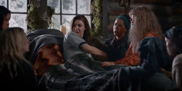 The girls surrounding Shauna (Sophie Nélisse) as she's about to give birth in Yellowjackets.