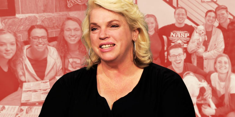 Sister Wives Janelle Brown smiling in black shirt red background