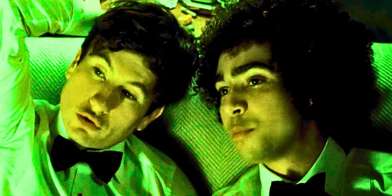 Oliver and Farleigh sitting close to one another on the couch in Saltburn