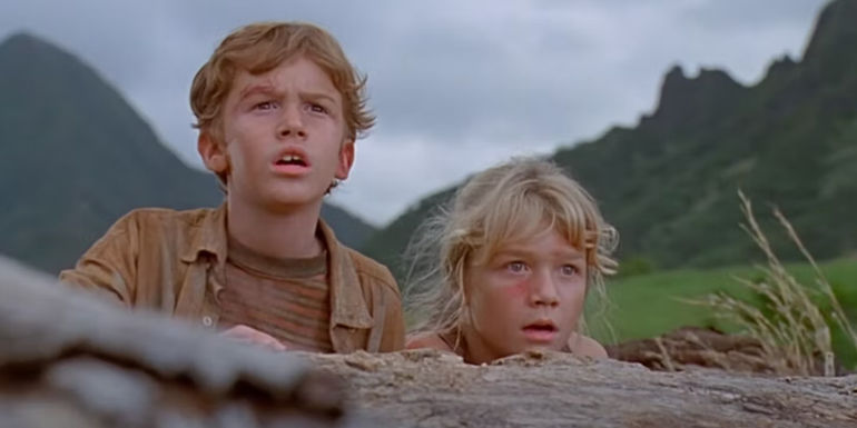 Lex and Tim look off-screen in Jurassic Park