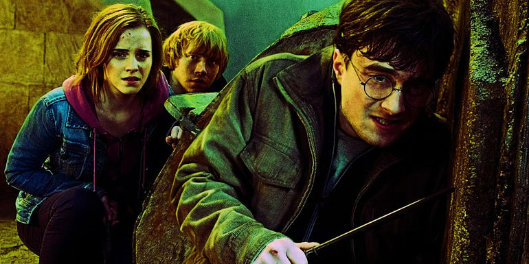 Daniel Radcliffe, Rupert Grint, and Emma Watson as Harry, Ron, and Hermione crouching on the ground during the Battle of Hogwarts in Harry Potter. 