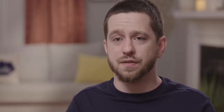 Clayton 90 Day Fiance talking to cameras blurred background dark shirt