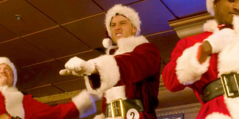 Ty (Justin Hartley) dancing in a santa outfit with other santas in A Bad Moms Christmas.