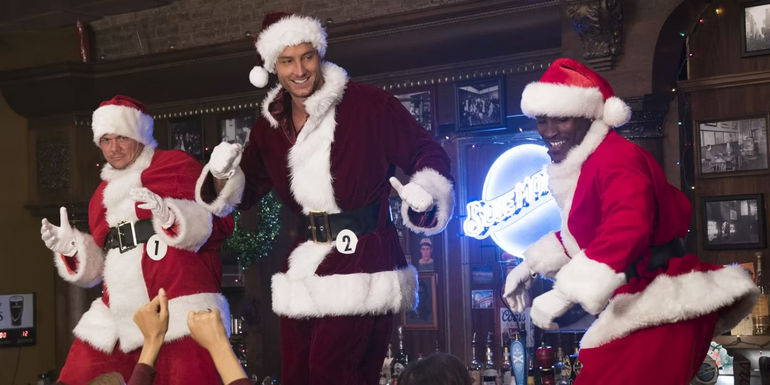 Ty (Justin Hartley) dancing with other santas on a bar in A Bad Moms Christmas.