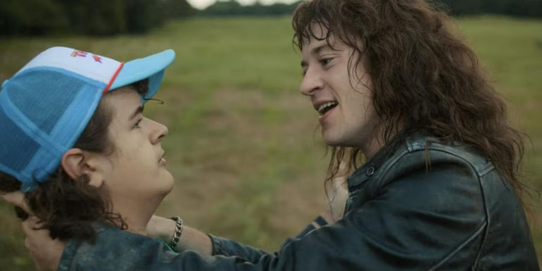 Eddie Munson embraces Dustin Henderson in a field in Stranger Things
