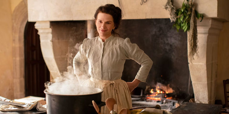 Juliette Binoche standing over a boiling pot in the kitchen in The Taste of Things