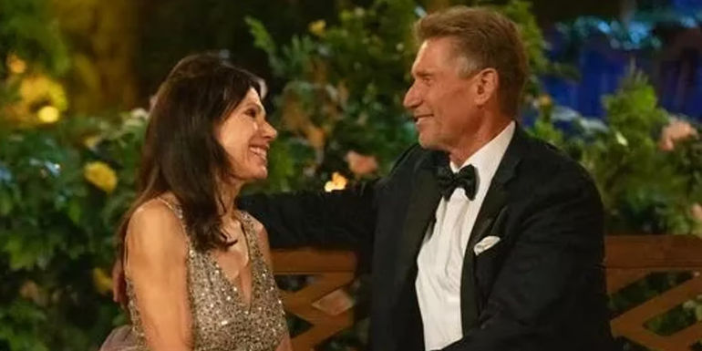 Theresa Nist and Gerry Turner from The Golden Bachelor laughing and looking at each other on bench