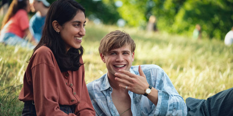 Emma and Dexter laugh together in a park in One Day