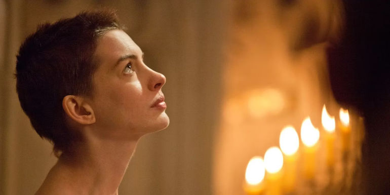 Fantine (Anne Hathaway) looking up in front of candles in Les Miserables.