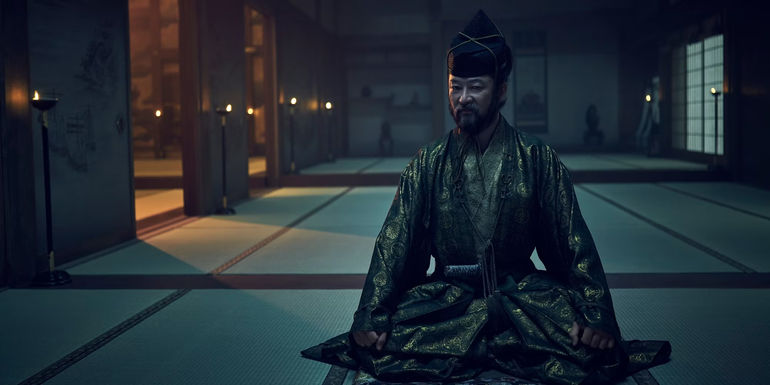 Yabushige sits on the floor with his head turned in Shogun