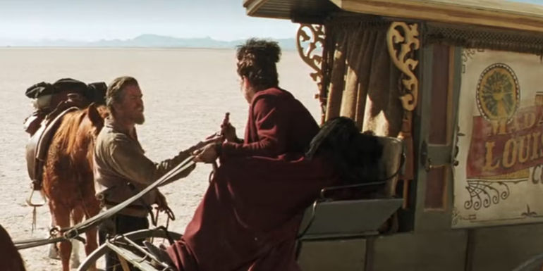 Gideon (Pierce Brosnan) reaches for a curative offered by Madame Louise (Anjelica Huston) in Seraphim Falls