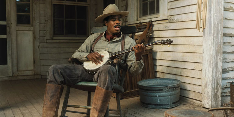 Colman Domingo as Mister plays the banjo on his porch in The Color Purple.