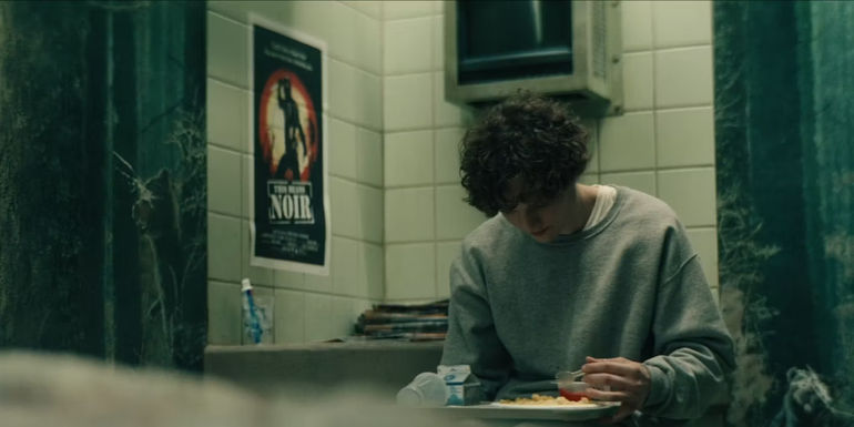 Sam sitting in his room in Goldolkin University's The Woods.