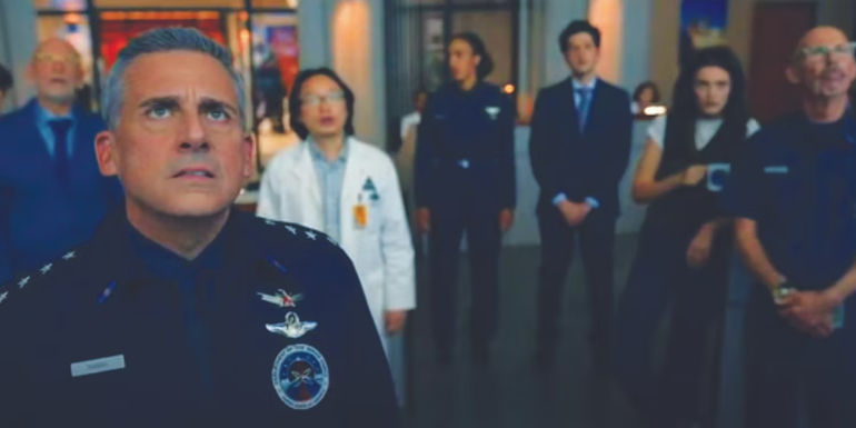 From L to R: John Malkovich as Dr. Adrian Mallory, Steve Carell as General Mark R. Naird, Jimmy O. Yang as Dr. Chan Kaifang, Tawny Newsome as Captain Angela Ali, Ben Schwartz as F. Tony Scarapiducci, Diana Silvers as Erin Naird, and Spencer House as Duncan Tabner looking up at the monitor in the Space Force finale