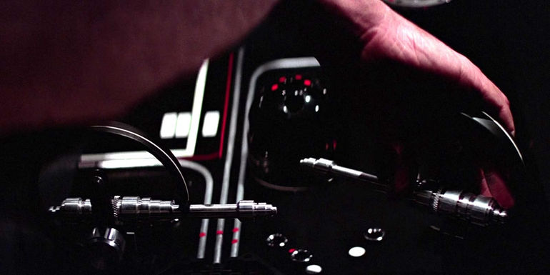 A closeup of Obi-Wan Kenobi (Alec Guinness) adjusting levers on the tractor beam on the Death Star in the original Star Wars