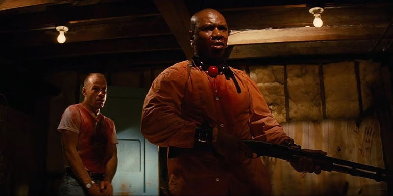 Ving Rhames as Marcellus holds a shotgun as Bruce Willis as Butch observes him while holding a katana in Pulp Fiction.
