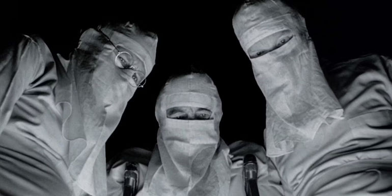 Masked surgeons look down on the camera in johnny got his gun 1979