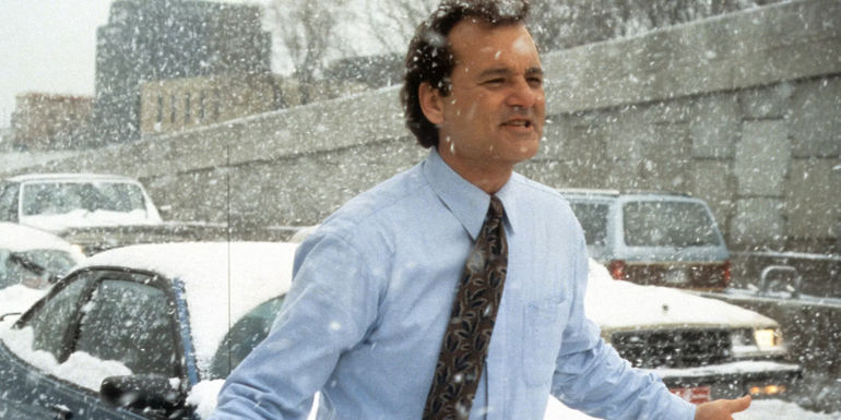 Phil (Bill Murray) walks through traffic in the snow in Groundhog Day. - Neither Phil nor the audience is supposed to be keeping track of the days - Not Knowing How Long Phil Was Trapped Is The Point Of Groundhog Day