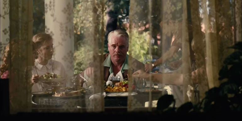 Dodd (Philip Seymour Hoffman) eating breakfast and staring off into the distance behind curtains in The Master.