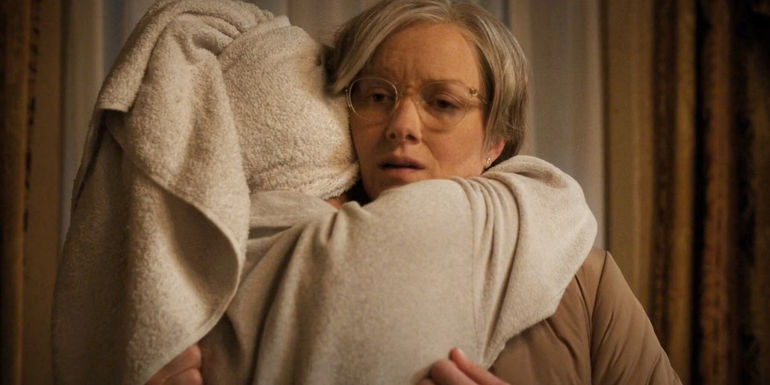 Aleida in a robe hugs Margo in her hotel room