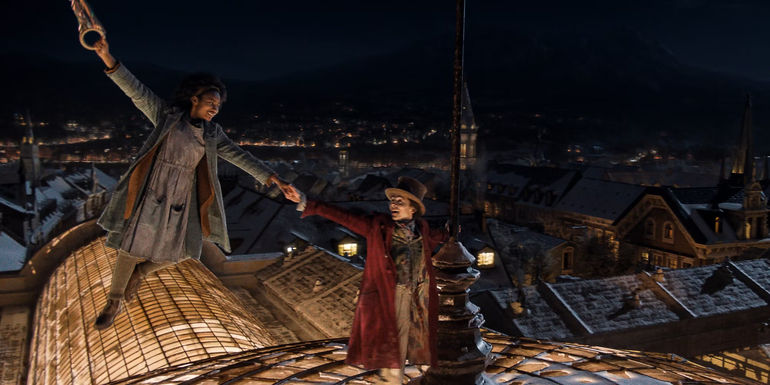 Willy Wonka (Timothée Chalamet) holding onto a floating Noodle (Calah Lane) on the top of a building in Wonka.