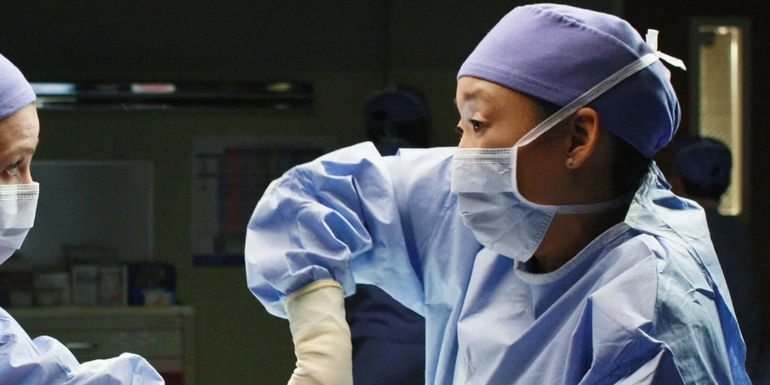 Christina Yangmasked and in surgical gear while working in an operating room in Grey's Anatomy