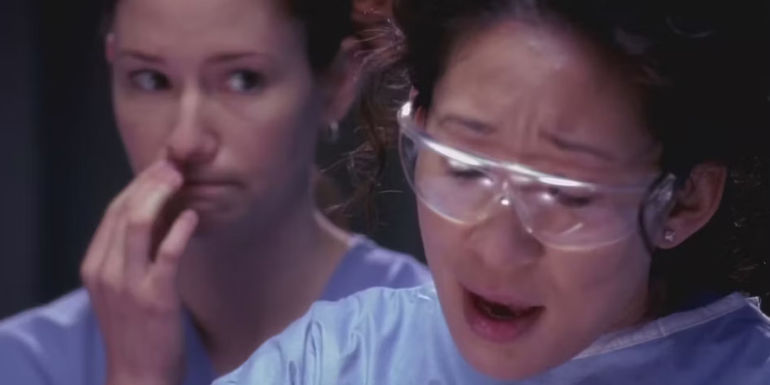 Lexie standing behind Christina while they work in Greys Anatomy