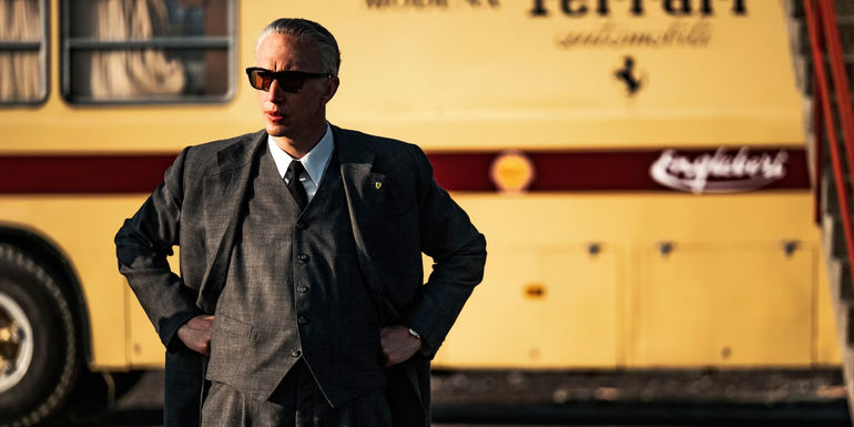 Adam Driver as Enzo Ferrari as he stands assessing in Ferrari