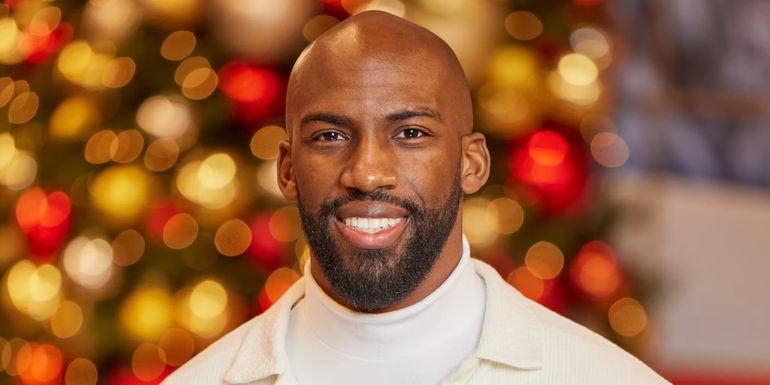 Big Brother Reindeer Games's Xavier Prather smiling in front of a Christmas tree