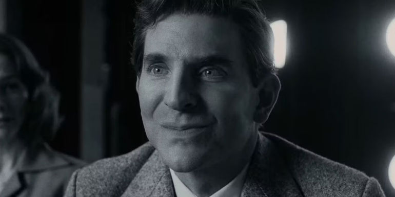 Bradley Cooper looking hopeful with a smile in Maestro