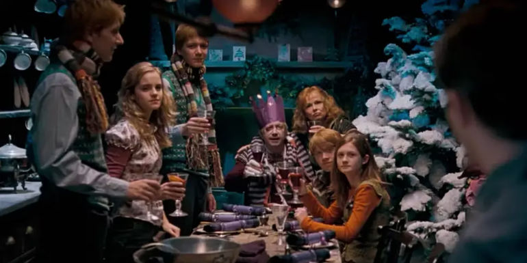 Hermione and the Weasley family, looking festive, are gathered around a table, raising glasses in a toast in harry Potter.