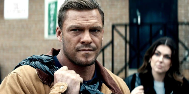 Alan Ritchson as Reacher holding a bag over his shoulder