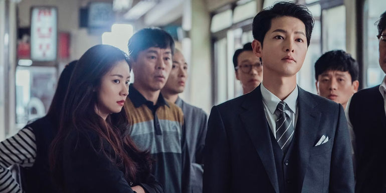 Vincenzo and Hong Cha-young standing around with a group of onlookers who all appear concerned.