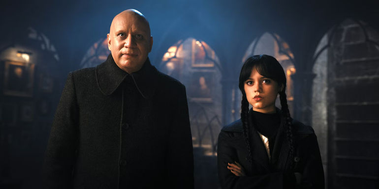 Wednesday and Fester standing side by side staring ahead